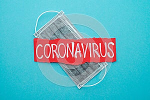 Text CORONAVIRUS on blue background and gray protect face mask with copy space. Global novel coronavirus Covid-19 outbreak