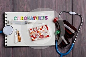 Text Coronavirus wooden letters on notebook, stethoscope and first aid kit on wooden background