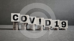 text covid-19 written on wooden blocks concept with downward stack of coins