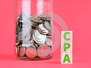 Text CPA on wooden cubes with coins against red background.