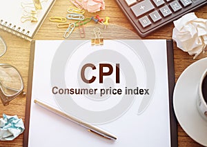 Text CPI - Consumer Price Index on a clipboard on office desk table with glasses, cup of coffee, calculator, notebook and crumbled