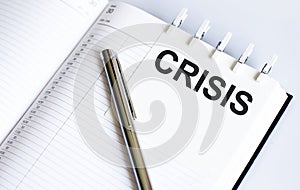 Text CRISIS on the short note texture background with pen