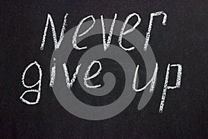 Text on a dark board `never give up` photo