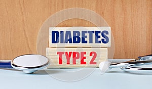 The text of the DIABETES TYPE 2 on wooden blocks and a stethoscope on the desktop. Clinic and medical business