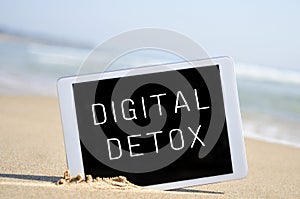 Text digital detox in a tablet computer, in the sand of a beach