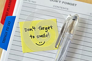 Text don`t forget to smile written on a sticky note over an agen