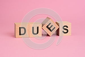 text dues on wooden cubes on pink table photo