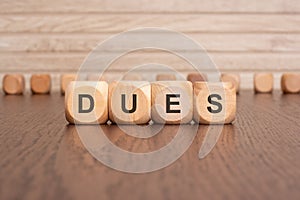 the text DUES is written on wooden cubes on a brown background photo