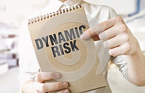 Text DYNAMIC RISK on brown paper notepad in businessman hands in office. Business concept