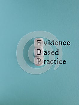 Text EBP Evidence-based practice concept on wooden cubes. Beautiful blue background.