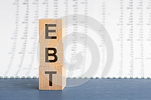 Text EBT on vertical row of wooden blocks on the background of columns of numbers