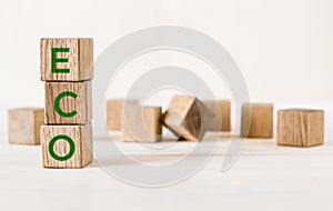 Text ECO is written on vertical wooden cubes on table with many wooden blocks