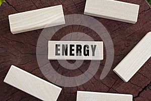 The text ENERGY is written on a wooden cube lying on an old tree stump.