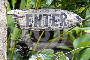 Text enter on a wooden board in a rainforest jungle of tropical Bali island, Indonesia. Enter wooden sign inscription in the asian
