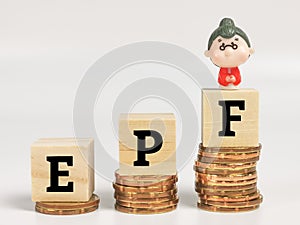 Text EPF on wooden cubes with stacked coins and miniature old woman.EPF stands for Employee Provided Fund.