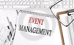 Text EVENT MANAGEMENT on Office desk table with keyboard, notepad and analysis chart on white background
