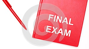 The text FINAL EXAM is written on a red notepad near a red pen on a white table in the office. Business concept