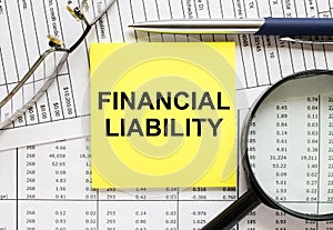 Text Financial Liability on financial tables with pen, glasses and magnifying glass