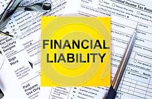 Text Financial Liability on note paper with the U.S IRS 1040 form,pen and glasses