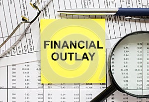 Text Financial Outlay on financial tables with pen, magnifying glass photo