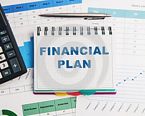 The text of the financial plan in a notebook on the background of a calculator, pen and financial papers