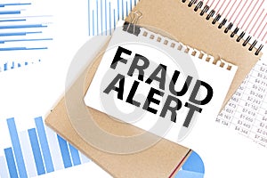 Text fraud alert on white paper sheet and brown paper notepad on the table with diagram. Business concept