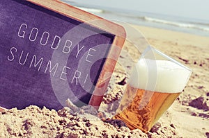 Text goodbye summer in a chalkboard and a glass of beer on the b