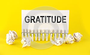 Text GRATITUDE on the white short note paper yellow background