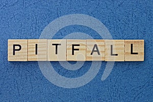 text on gray word pitfall in small wooden letters with black font