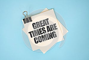 Text GREAT TIMES ARE COMING on sticky notes with copy space and paper clip isolated on red background. Finance and economics