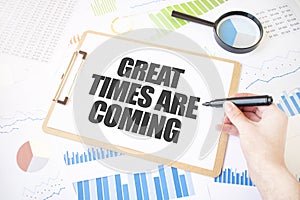 Text GREAT TIMES ARE COMING on white paper sheet and marker on businessman hand on the diagram. Business concept