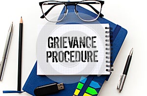 Text grievance procedure on notepad with office tools, pen on financial report