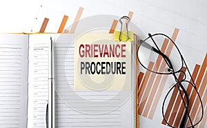 Text GRIEVANCE PROCEDURE on sticker on the notepad on diagram background