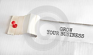 The text GROW YOUR BUSINESS appearing behind torn yellow paper