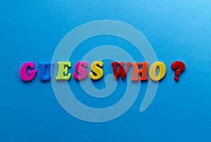 Text guess who? from plastic colored letters on blue paper background