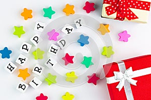 The text `happy birthday` arranged from blocks on a white background, next to colorful stars and gift boxes