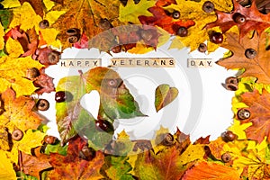 The text Happy Veterans Day written on a whiteboard and autumn leaves and heart shape.