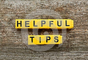 Text Helpful Tips made of yellow cubes with letters on wooden table, top view