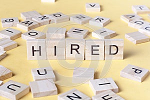 Text of HIRED on cubes. Wooden abc