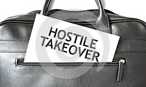 Text HOSTILE TAKEOVER writing on white paper sheet in the black business bag. Business concept