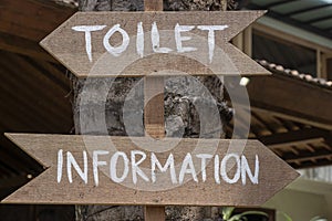 Text information and toilet on a wooden board of tropical Bali island, Indonesia. Information and toilet wooden sign inscription