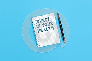 The text Invest in your health is written on a notebook page