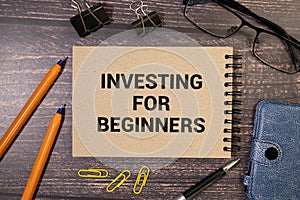text Investing for Beginners on green sticker and wooden background