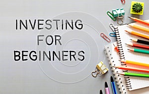 text Investing for Beginners on green sticker and wooden background.