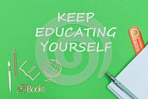 Text keep educating yourself, school supplies wooden miniatures, notebook on green background