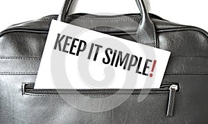 Text KEEP IT SIMPLE writing on white paper sheet in the black business bag. Business concept