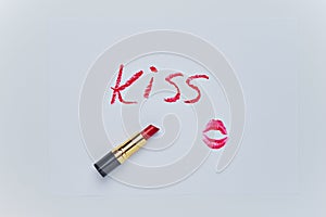 Text KISS drawing and trace of kiss by red lipstick on white sheet