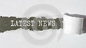 the text LATEST NEWS appearing behind torn white paper, gray background