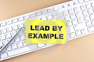 Text LEAD BY EXAMPLE text on a sticky on keyboard, business concept