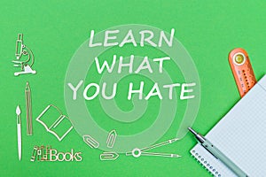 Text learn what you hate, school supplies wooden miniatures, notebook with ruler, pen on green backboard